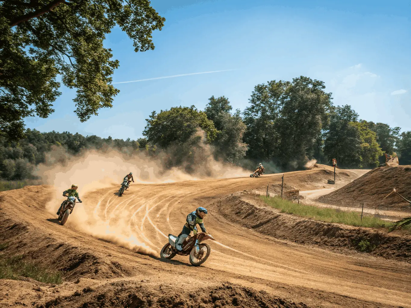 An action shot of experienced riders navigating a challenging motocross track during a supervised practice, highlighting skill and precision.